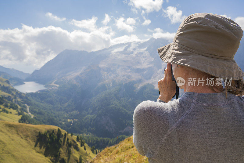 年长妇女的后视图肖像拍摄的湖Fedaia和马尔莫拉达山在Viel dal Pan路径在多洛米特，意大利北部。